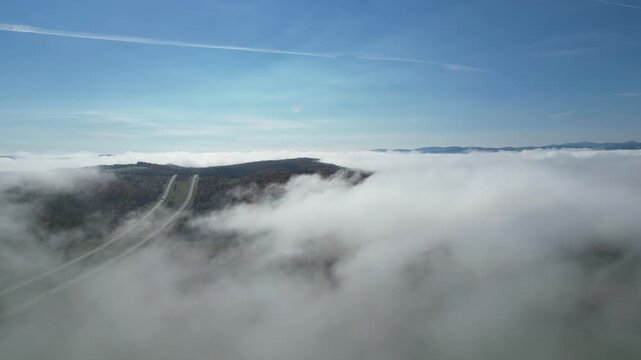 Aerial flight above a sea of morning fog with a mountain rising through the clouds, autumn in Vermont