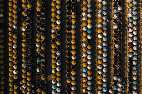 Aerial view of rows of circular fish sauce vats with conical lids arranged in a production facility in Mui Ne, Binh Thuan, Vietnam.