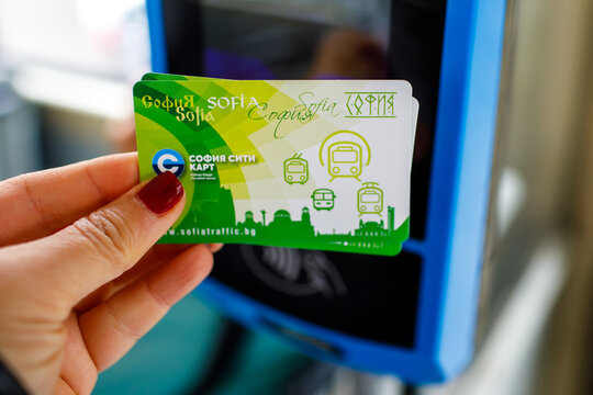 Sofia. Bulgaria. 13.10.2026 Hand with dark red manicure holding green transport card at validator in tram, transport card payment, transport card with grainy film texture, high quality photo