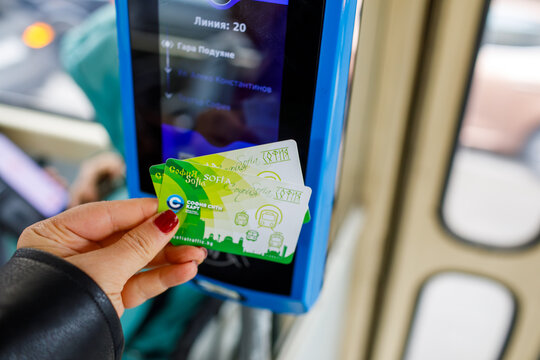 Sofia. Bulgaria. 13.10.2026 Hand with dark red manicure holding green transport card at validator in tram, transport card payment, transport card with grainy film texture, high quality photo