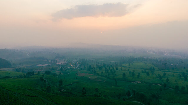Aerial view of Wayang Windu Panenjoan tea plantations with rolling green hills, winding paths, and misty atmosphere in the highlands, Pangalengan, West Java, Indonesia.
