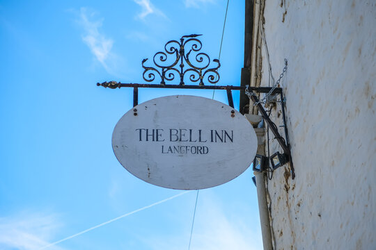 Langford, UK - April 6, 2026. Hanging Sign of The Bell Inn Country Pub in Langford Cotswolds. A high-detail horizontal close-up photograph showcasing the traditional hanging oval sign of The Bell Inn 