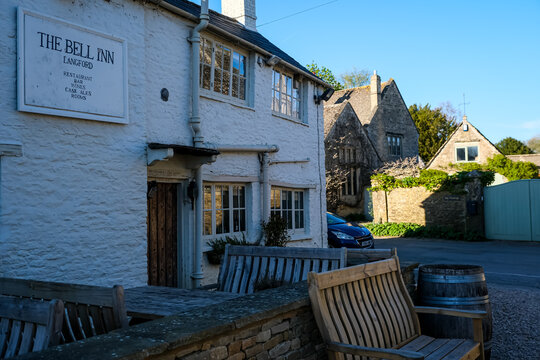 Langford, UK - April 7, 2026. Traditional Historic Country Pub The Bell Inn in Langford Village Cotswolds. A high-detail horizontal photograph capturing the exterior facade of The Bell Inn, a classic 