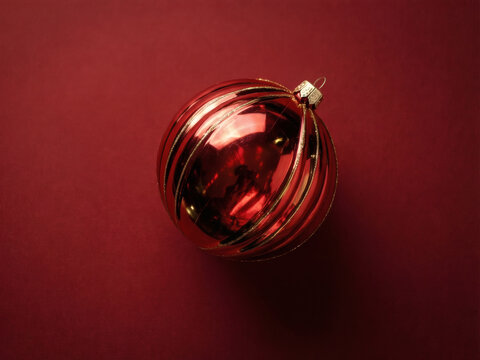 Red Christmas ornament with gold reflection on a crimson backdrop for the holiday season