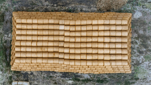 Aerial view of a large stack of cylindrical hay bales arranged in neat rows on a field in Utrine, Vojvodina, Serbia.