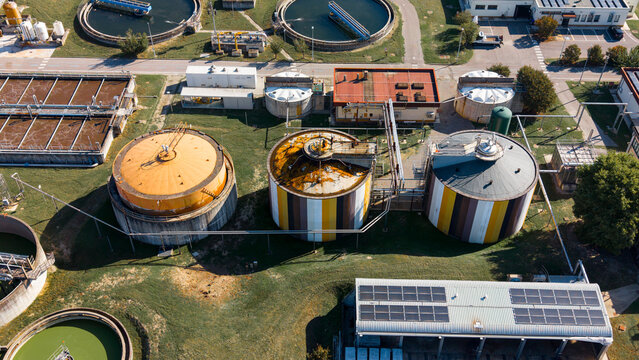 Aerial view of a wastewater treatment plant with large circular sedimentation tanks and industrial infrastructure in Rancate, Lombardia, Italy.