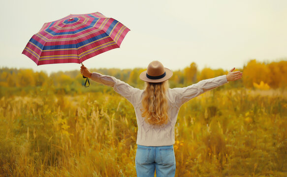 happy woman in autumn park with umbrella, enjoying warm sunny weather