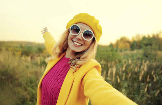 Portrait of happy smiling woman taking selfie with phone in park