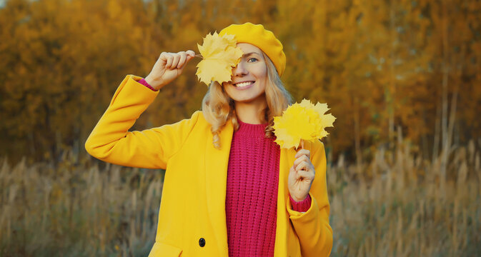 Happy woman with autumn yellow leaves, cheerful girl smiling outdoors