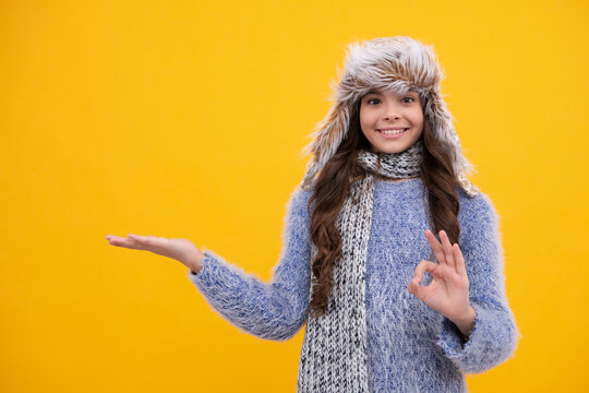 Teenager girl with winter hat over isolated yellow background. Winter christmas holidays, new year mood. Kids warm clothes. Happy face, positive and smiling emotions of teenager girl.