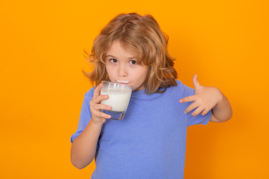 Organic milk. Child with a glass of milk on studio background. Cute boy in white shirt holding glass of milk on isolated on yellow. Portrait of kid with milk mustache.