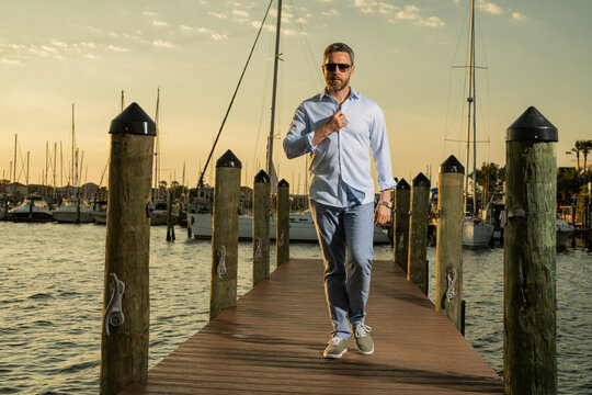 Fashion business man near the yacht. Portrait of fashion model outdoor. Fashion male posing near yachts. Fashion man in urban style. Handsome hispanic man at yacht club. Man in gulf near luxury yacht.