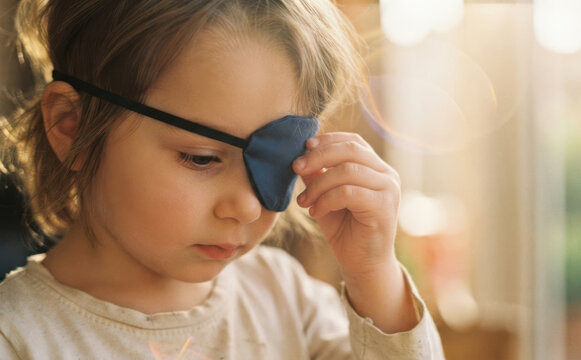 Young Caucasian toddler girl wearing an eye patch for amblyopia and strabismus treatment therapy at home