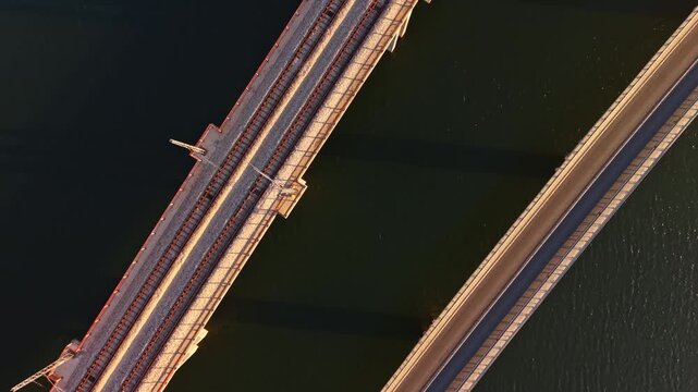 Aerial view of parallel railway and road bridges crossing a river, with tracks and traffic lanes visible in daylight.