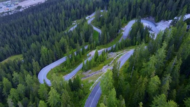 Aerial view of a steep winding switchback road in an alpine pine forest