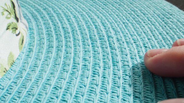 Straw hat texture in turquoise color, close up of woman hand touching blue woven summer hat, handmade crochet material in fashion shop and accessories production