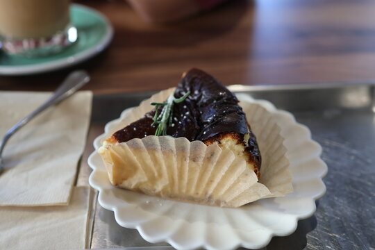 Slice of burnt Basque cheesecake with rosemary in a paper cup