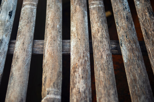 Perspective close up of weathered split bamboo slat texture with selective focus.
A high-quality close-up photograph capturing the rustic and organic texture of aged bamboo slats arranged in a paralle