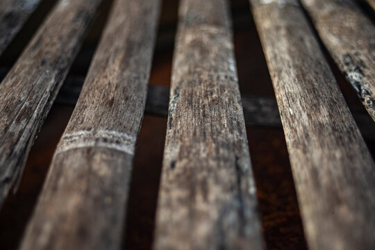 Perspective close up of weathered split bamboo slat texture with selective focus.
A high-quality close-up photograph capturing the rustic and organic texture of aged bamboo slats arranged in a paralle