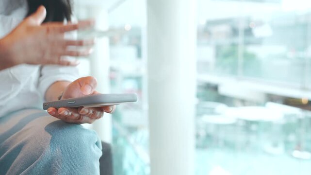Woman using smartphone at modern city cafe, scrolling social media, texting and brushing hair during casual break, urban lifestyle with blurred pedestrians outside window  for advertising