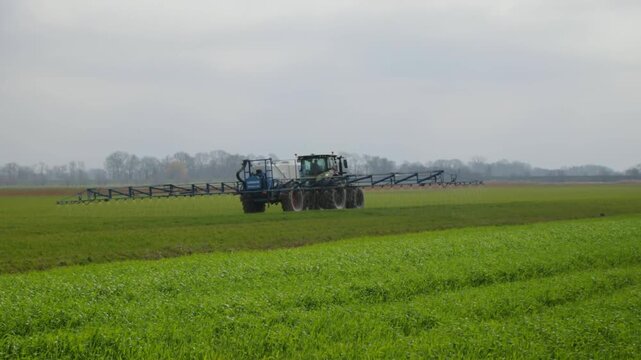 Tractor fertilising field, near Krummendeich, Lower Saxony, Germany