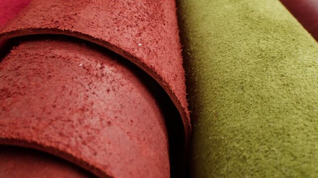 Leather rolls samples in red, green and brown colors, close up of colorful genuine leather swatches in leather shop, tannery factory production and material catalog