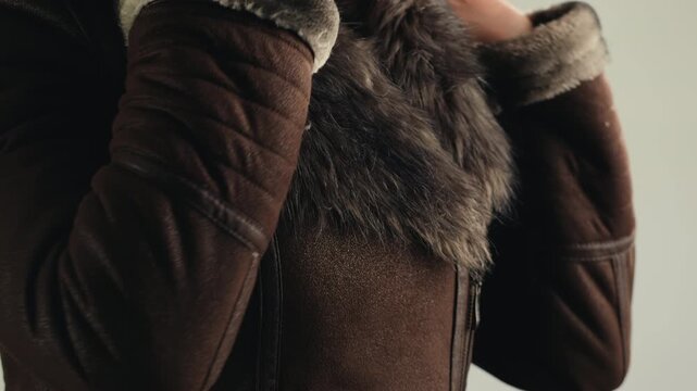 Sheepskin coat with fox fur collar, close up of woman in leather jacket with fluffy fur hood, warm shearling outerwear in fur shop from Turkish leather factory production