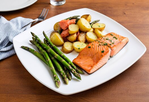 Delicious grilled salmon with roasted potatoes and asparagus on a white plate