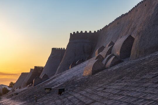 Khiva, Uzbekistan. The ancient city walls of the Itchan Kala, the fortified inner town, at dusk. In the foreground are old mud-brick tombs