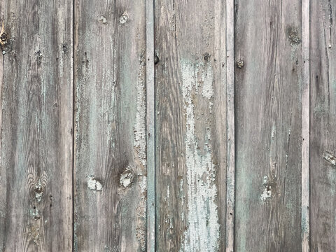 Weathered vertical wooden planks with peeling pale green paint and rustic textured grain surface for background use, textured close-up paneling ideal for design projects and architectural visuals.