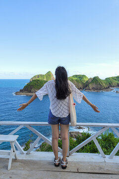 Back View Of Female Tourist Enjoying Freedom And Scenic Coastal Views At Lookoout Point