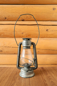 An antique kerosene lantern set in front of rustic log cabin wall