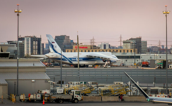 Toronto, Ontario, Canada - 05 26 2026: Large Volga-Dnepr Antonov An-124 cargo airplane parked at Toronto Pearson International Airport tarmac at dusk with city skyline
