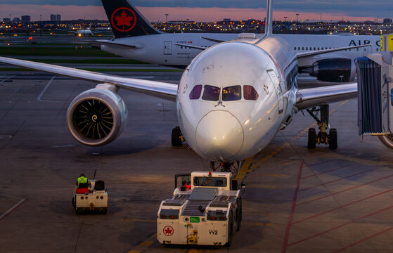 Toronto, Ontario, Canada - 05 26 2026: Front view of Air Canada Boeing 787 Dreamliner at jet bridge with pushback tractor on tarmac at dusk