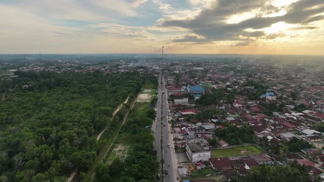 Aerial view of a small town with a main road running through residential areas and buildings under a daytime sky. Urban landscape, transportation, and community travel concept.