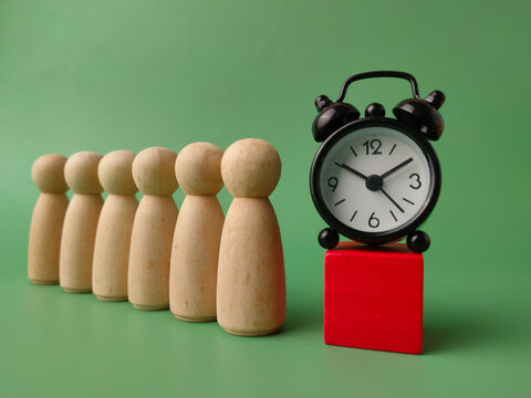 Black Alarm Clock on Red Block Next to Wooden Figures