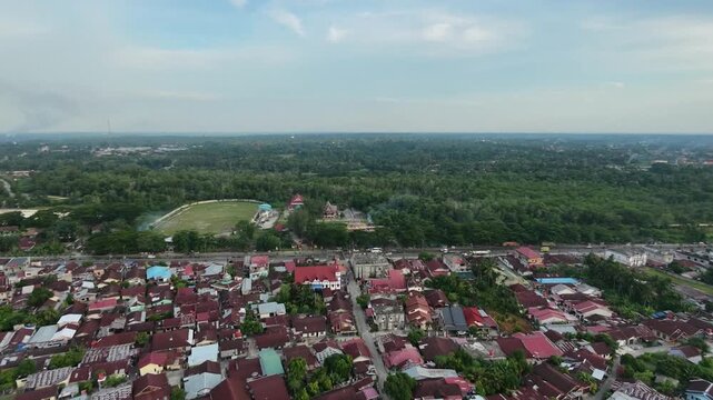 Aerial view of a small town with a main road running through residential areas and buildings under a daytime sky. Urban landscape, transportation, and community travel concept.