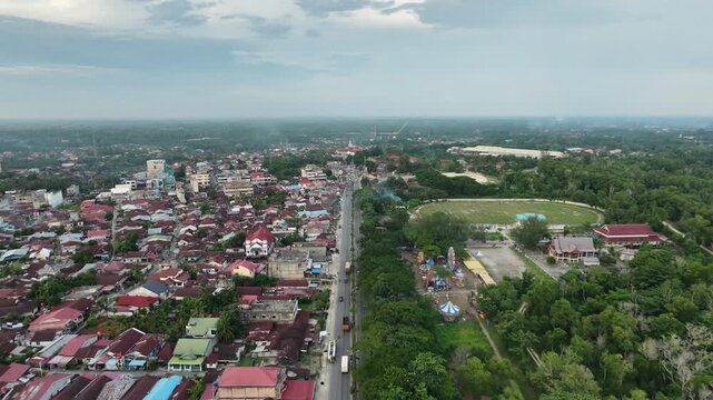 capturing a regional town layout featuring a busy street, neighborhood housing, and surrounding green nature. Urban geography and daylight environment concept