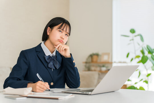 High School Girl in School Uniform Studying on a Laptop in Her Living Room at Home, Thinking About Her Future Education and Career Path