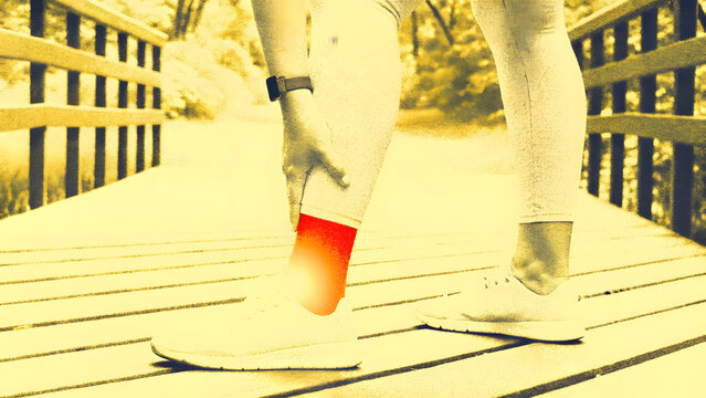 Athlete experiencing foot pain or injury during outdoor running on wooden bridge path