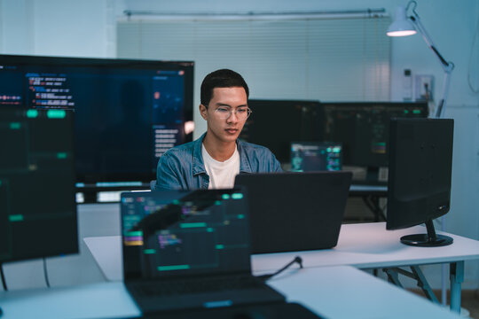 Software Developer Coding At Multi Monitor Workstation.