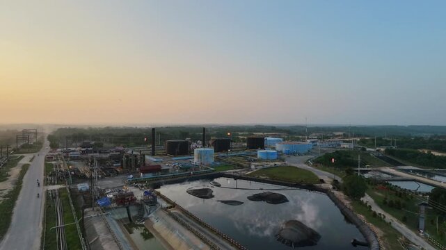 Aerial view of an industrial wastewater treatment facility with storage ponds and processing tanks near an industrial plant under a clear sky. Environmental management and industry concept.