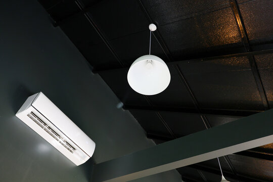 Black ceiling, white round pendant light, and wall mounted air conditioner in modern interior