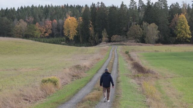 Linkoping, Sweden A man walks on a country path with autumn foliage.  