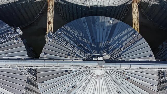 A large radio telescope dish fills the view at an observatory, with metal panels and support structures seen from above in daylight.