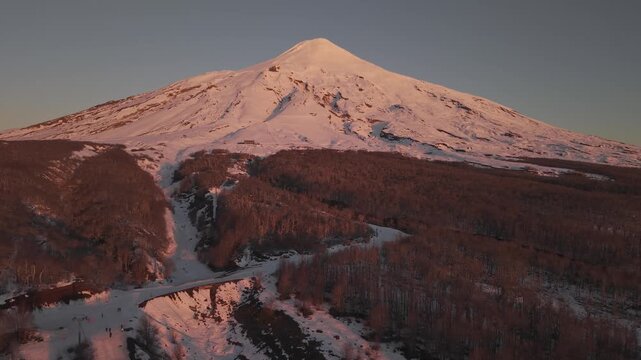 Alpenglow on Villarrica volcano with snowy lava channels, aerial