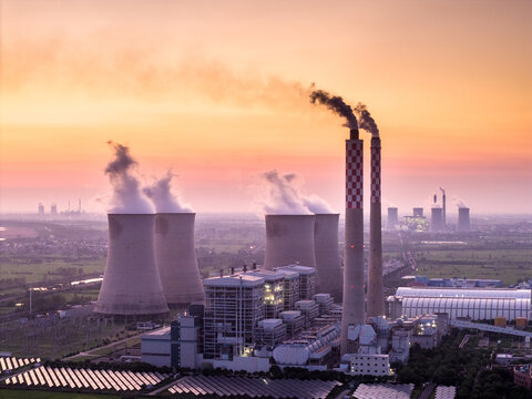 power plant at sunset with cooling towers and smoke stacks
