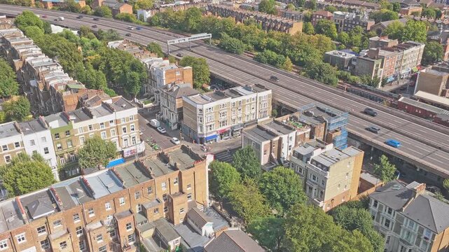 Westway A40 elevated dual carriageway and parallel railway tracks beside residential blocks in Notting Hill area, Kensington and Chelsea, Greater London, England, United Kingdom, drone descent