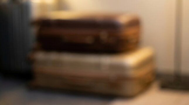 Blurred abstract background of two vintage stacked polished leather travel suitcases in a cozy room, symbolizing preparation for a journey, luxury tourism, and global adventure lifestyle.
