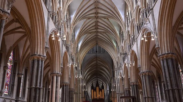 Tall Gothic arches and ribbed vaulting line the nave of Lincoln Cathedral, viewed straight down the aisle with soft interior lighting.